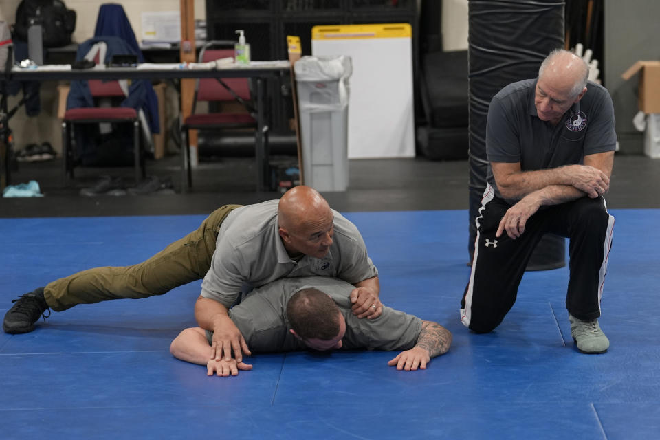 Instructor Dave Rose, right, watches as fellow instructor Enrico Solomon, top, demonstrates the basics of ground control on a student during an Arrest & Control Instructor course in Sacramento, Calif., on Thursday, Jan.18, 2024. Law enforcement officers from various agencies attend the class where they receive instruction on basic techniques of arrest and control that they to take back to their agencies to pass along to fellow officers. (AP Photo/Rich Pedroncelli)