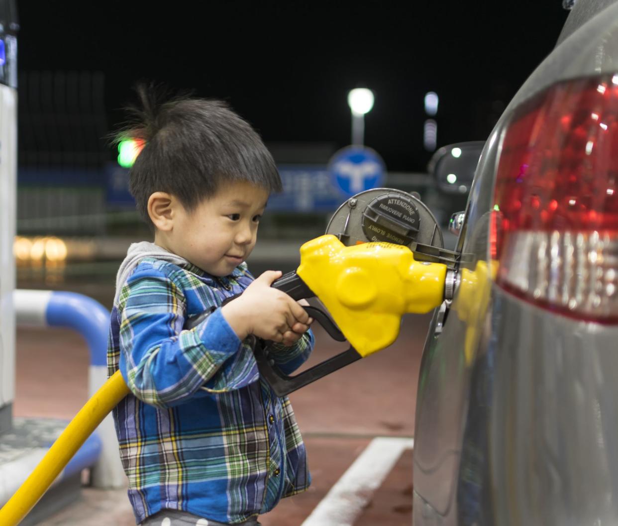 child putting oil in a gas station