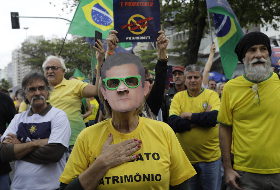 A woman wears a mask of Brazil's Justice Minister Sergio Moro during a rally in support of the government's "Car Wash" investigation into corruption on Copacabana beach, in Rio de Janeiro, Brazil, Sunday, Aug. 25, 2019. Supporters of the president and the justice minister called for the nationwide demonstration. (AP Photo/Silvia Izquierdo)