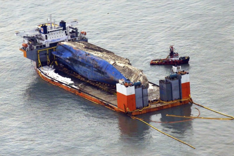 2014年4月沉沒、奪走304條人命的南韓渡輪「世越號」26日被抬到半潛船上，準備運往木浦新港（AP）