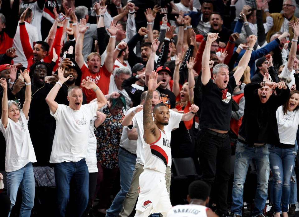 Damian Lillard waves goodbye as fans cheer behind him.