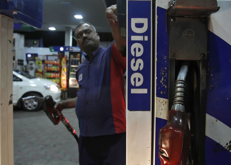 A worker switches on a fuel pump before filling a car with diesel at a fuel station in New Delhi