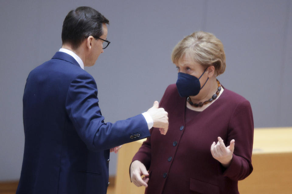 Poland's Prime Minister Mateusz Morawiecki, left, speaks with German Chancellor Angela Merkel during a round table meeting at an EU summit in Brussels, Friday, Oct. 22, 2021. European Union leaders conclude a two-day summit on Friday in which they discussed issues such as climate change, the energy crisis, COVID-19 developments and migration.(AP Photo/Olivier Matthys, Pool)