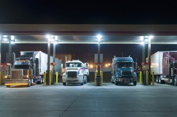 Semi trucks refueling at a truck stop.