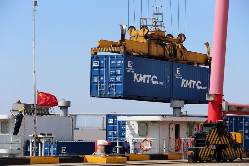 Crane lifts containers to be loaded onto a cargo vessel at a port in Qidong city of Nantong