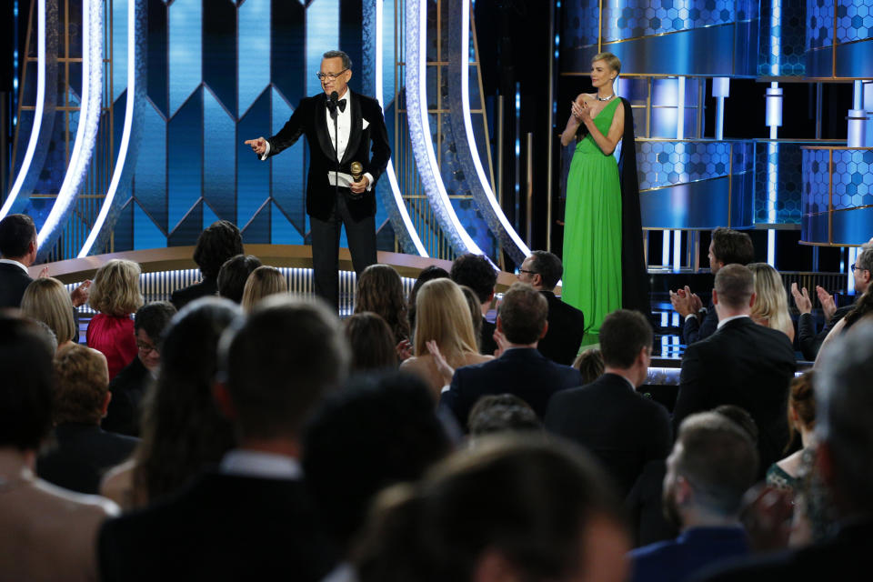 This image released by NBC shows Tom Hanks accepting the Cecil B. DeMille Award as presenter Charlize Theron looks on at right at the 77th Annual Golden Globe Awards at the Beverly Hilton Hotel in Beverly Hills, Calif., on Sunday, Jan. 5, 2020. (Paul Drinkwater/NBC via AP)