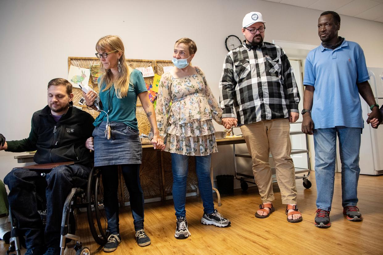 Dustin Mailman, associate pastor at Trinity Methodist in West Asheville, second from right, stands between Khristie and Jeffery Glenn as they say grace before their last meal together on the final day of Code Purple, March 31, 2022.