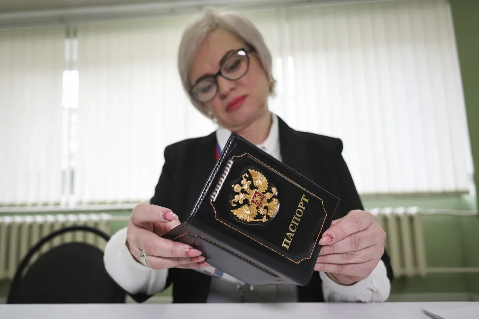 An election commission official inspects the passport of a person who came to vote at a polling station, during a presidential election in Makiivka, Russian-controlled Donetsk region, eastern Ukraine, Friday, March 15, 2024. People in Moscow-controlled Ukrainian regions are voting in Russia's presidential election, which is all but certain to extend President Vladimir Putin's rule after he clamped down on dissent. (AP Photo)