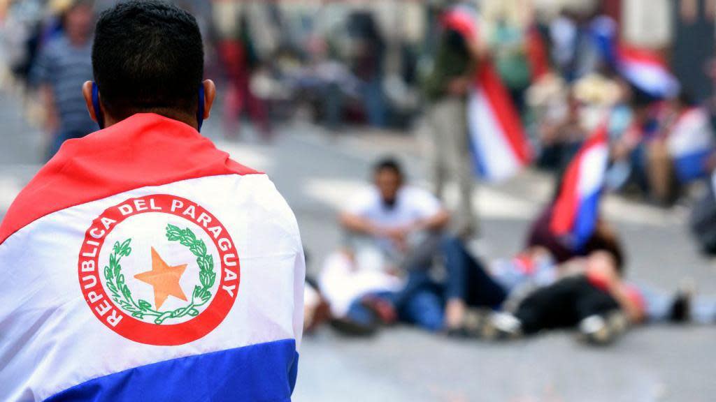 Hombre con la bandera de Paraguay sobre sus hombros y espalda.