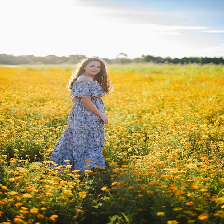 Model wearing a prairie style dress in a field of flowers