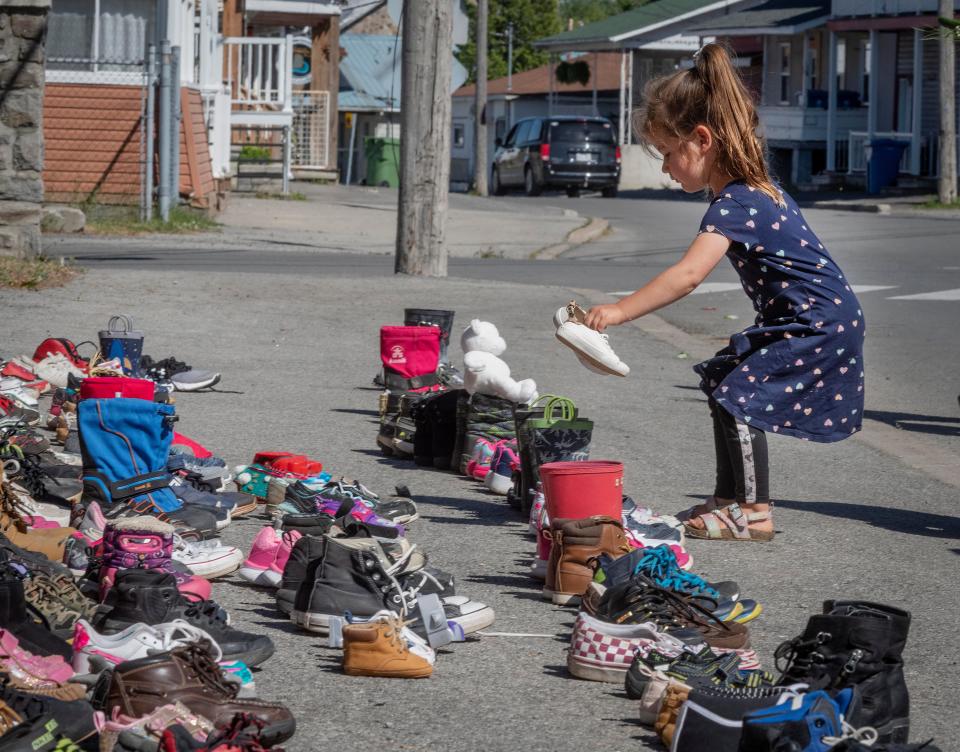 A four-year-old girl places a pair of her own shoes in front of the St. Francis Xavier Church St. Francis Xavier Church in Kahnawake, Quebec on Saturday, May 29, 2021, as a memorial to the 215 children whose remains have been found buried at the site of a former residential school in Kamloops.