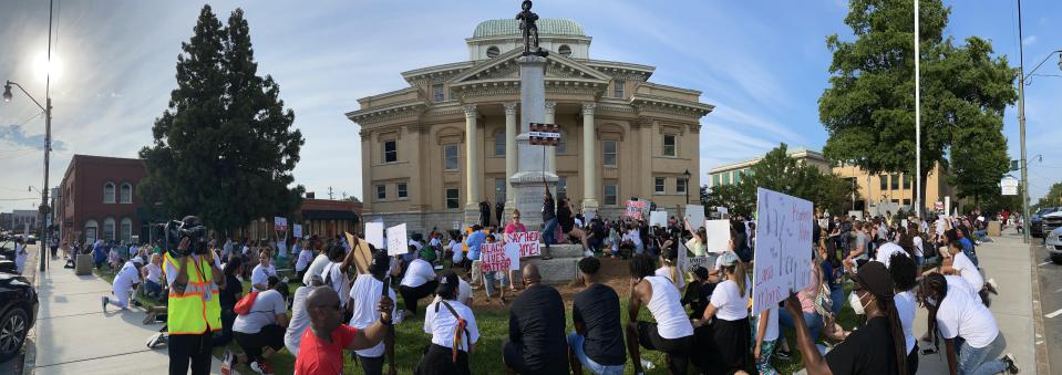 Protesters kneel around the Confederate statue in front of the historic courthouse during a demonstration in 2020.