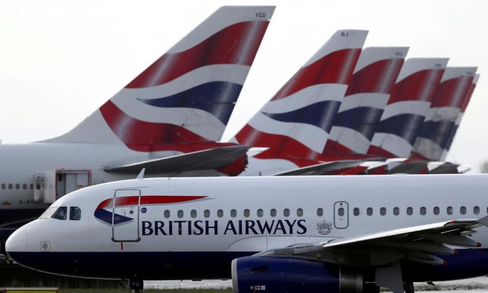 BA plane taxis past tail fins of parked aircraft