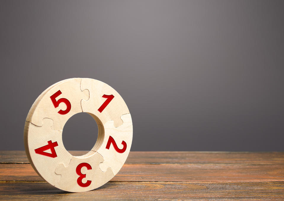 Image of a numbered wooden puzzle ring on a wooden table.