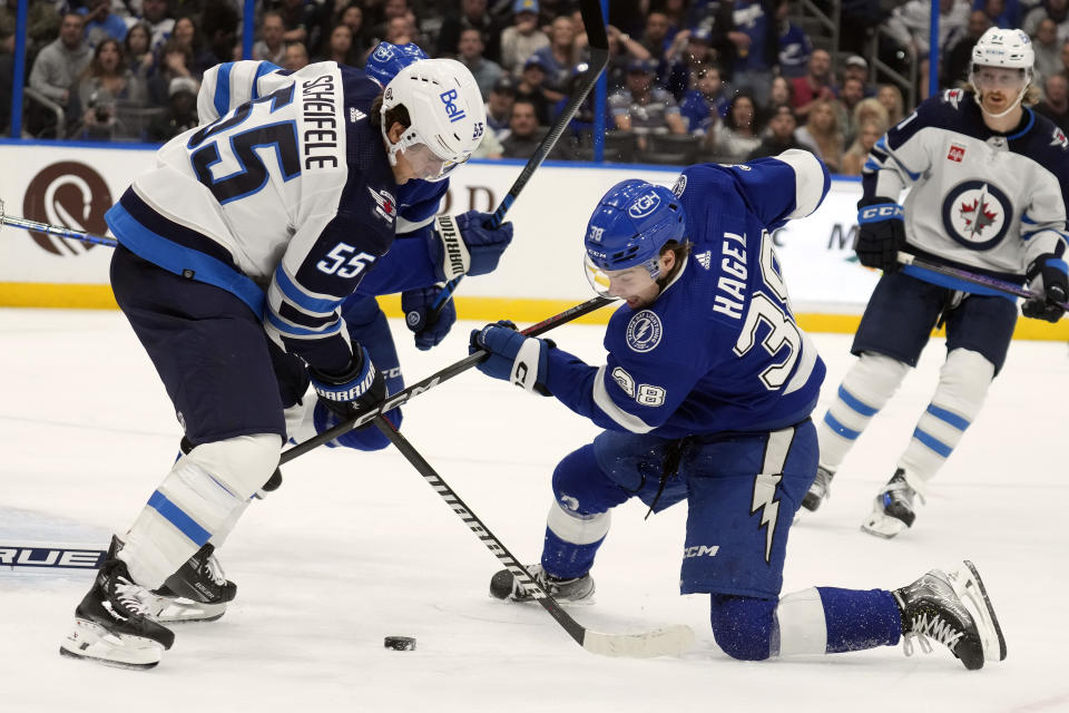 Winnipeg Jets center Mark Scheifele (55) and Tampa Bay Lightning left wing Brandon Hagel (38) try to play the puck during the second period of an NHL hockey game Wednesday, Nov. 22, 2023, in Tampa, Fla. (AP Photo/Chris O'Meara)