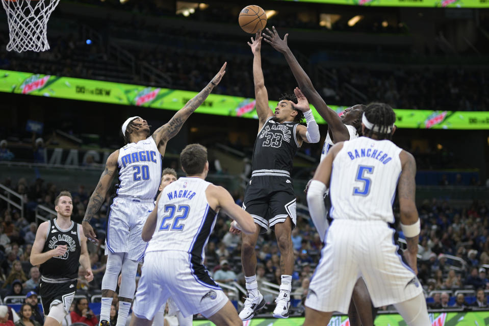 San Antonio Spurs guard Tre Jones (33) shoots between Orlando Magic guard Markelle Fultz (20), forward Franz Wagner (22), forward Paolo Banchero (5) and center Bol Bol, back right, during the first half of an NBA basketball game Friday, Dec. 23, 2022, in Orlando, Fla. (AP Photo/Phelan M. Ebenhack)