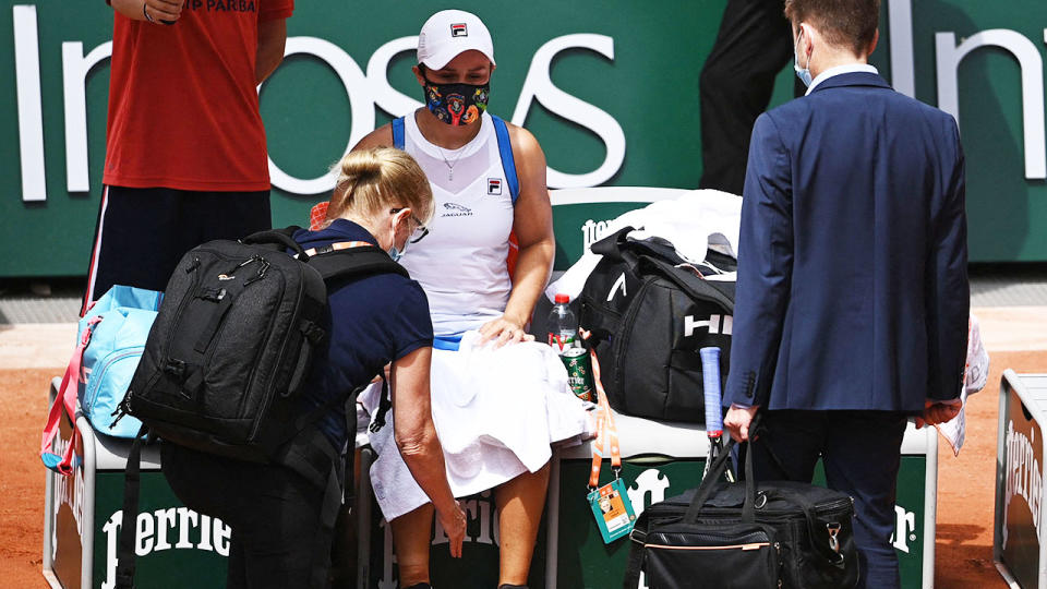 Ash Barty, pictured here being treated by medical staff during her match against Magda Linette.