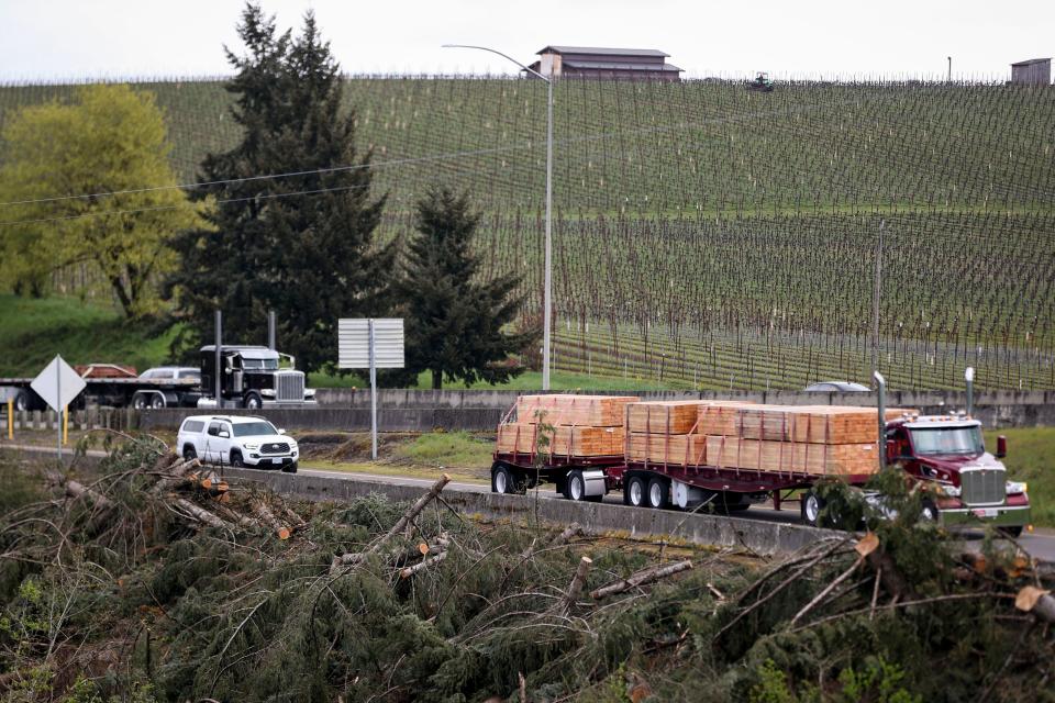 Trees and branches are piled along the guardrail of the Delaney Road Exit off southbound Interstate 5.
