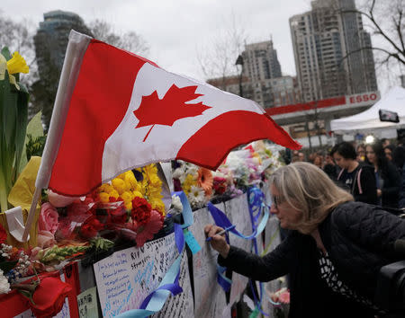 A mourner writes a message on a makeshift memorial a day after a van struck multiple people along a major intersection in north Toronto, Ontario, Canada, April 24, 2018. REUTERS/Carlo Allegri