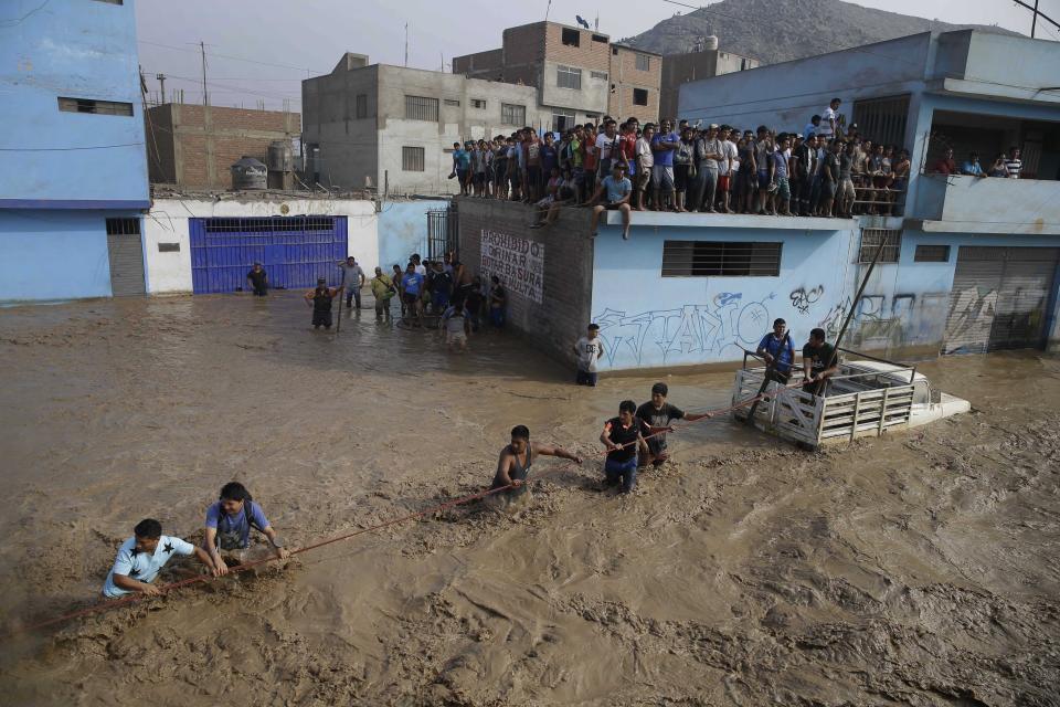 Un grupo de personas, atrapados en las aguas de las inundaciones, se aferran a una cuerda mientras caminan en Lima, Perú, el viernes 17 de marzo de 2017. Intensas lluvias y deslizamientos de lodo durante los últimos tres días han causado estragos en la nación andina y atrapado a residentes en Lima. (AP Foto/Martin Mejía)