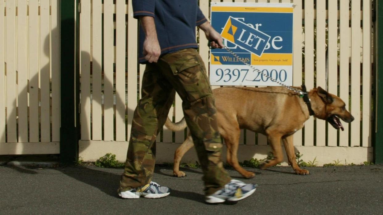 Man walking dog past for rent sign
