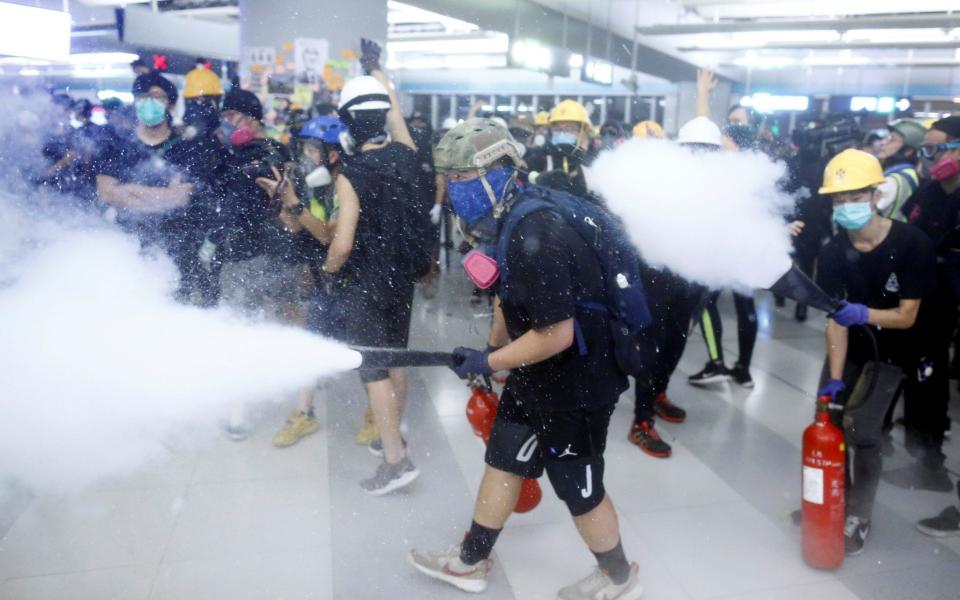 Protesters fire nitrogen extinguishers during a stand off at Yuen Long MTR station - REUTERS