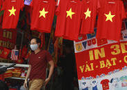 A man walks past a row of T-shirts printed with Vietnamese flags in Hanoi, Vietnam on Thursday, Jul.30, 2020. For 99 days, Vietnam seemed to have defeated the coronavirus, but now a new outbreak in the city of Da Nang has grown to over 40 cases in six cities and authorities are beginning to reimpose broader restrictions. (AP Photo/Hau Dinh)