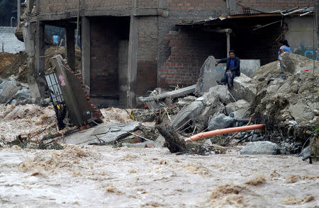 Man sits near a flooded home after the Rimac river overflowed near the Central Highway in Huarochiri, Lima, Peru, March 23, 2017. REUTERS/Guadalupe Pardo