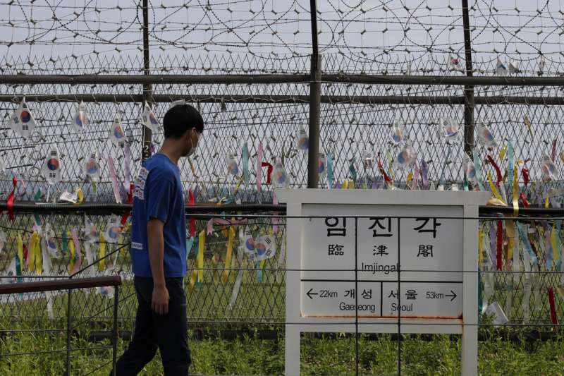 一名遊客在南北韓交界附近的臨津閣遊覽。隨處可見的彩帶上寫著「希望兩韓統一」，立牌上寫的是當地與開城（北韓大城）及首爾（南韓首都）的距離。 （美聯社）
