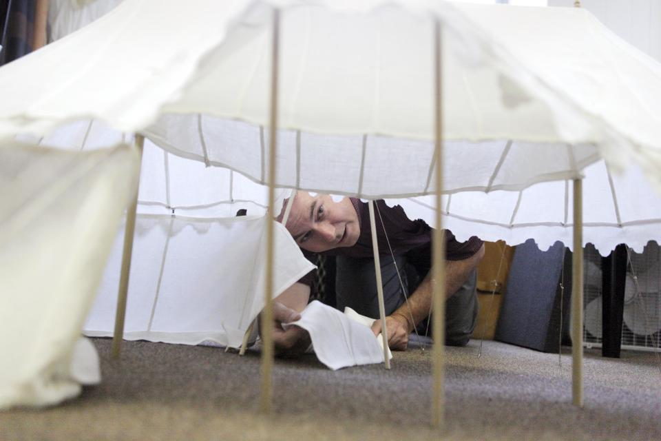 In this Thursday, June 28, 2012 photo Scott Stephenson, the director of Collection and Interpretation looks under the scale model of Gen. George Washington's sleeping and office tent, to study and mount the original canvas marquee for a museum in Philadelphia. This artifact and others hidden treasures will remain under wraps in their anonymous location until late 2015, when The Museum of the American Revolution is scheduled to open in Philadelphia's historic district. (AP Photo/Brynn Anderson)