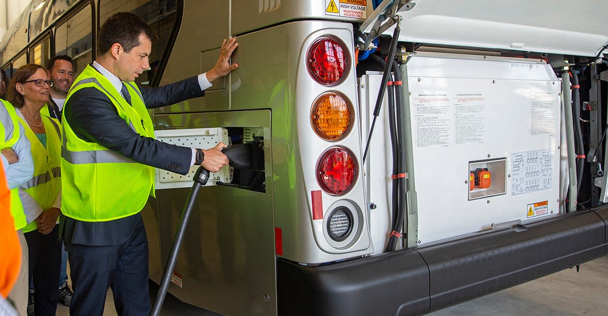 Secretary of Transportation Pete Buttigieg unplugs a bus from the recharging station in July 2021 in the Lane Transit District garage in Springfield.