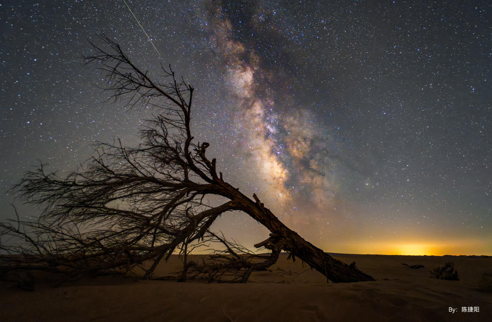 An astrophotography image of the milky way with a fallen tree in the foreground taken with the TTArtisan APS-C 10mm f/2 ASPH