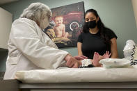 Dr. Sara Goza explains an infant's upcoming vaccinations to his mother in an exam room at First Georgia Physician Group Pediatrics in Fayetteville, Ga., Tuesday, Aug. 17, 2021. The vaccinations that U.S. schoolchildren are required to get to hold terrible diseases like polio, hepatitis, tetanus and whooping cough in check are way behind schedule this year, threatening further complications to a school year already marred by COVID-19. (AP Photo/Angie Wang)