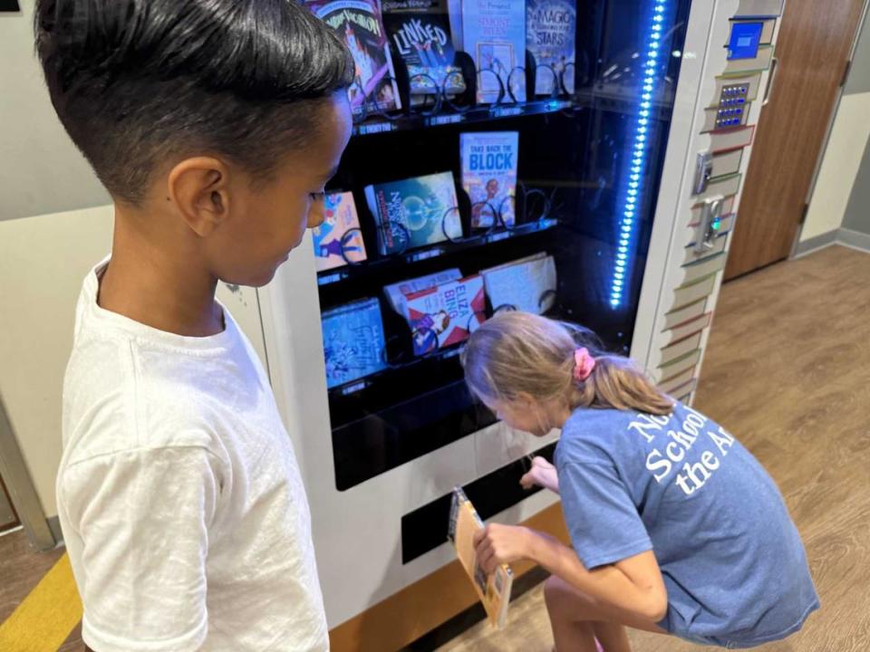 Peyton Vaughn, 7, watches Amelia Vollchansky, 9, grab a new book from the vending machine July 17 at the Rancho Cordova Youth Center.