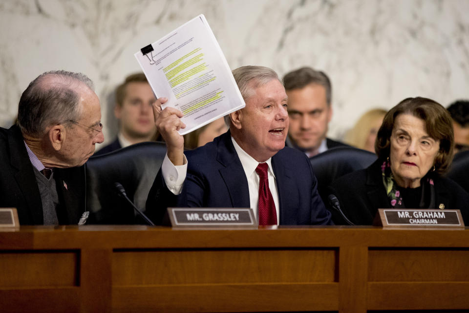 Chairman Lindsey Graham, R-S.C., center, accompanied by Sen. Chuck Grassley, R-Iowa, left, and Ranking Member Sen. Dianne Feinstein, D-Calif., right, holds up a report while giving an opening statement as Department of Justice Inspector General Michael Horowitz, center foreground, testifies at a Senate Judiciary Committee hearing on the Inspector General's report on alleged abuses of the Foreign Intelligence Surveillance Act, Wednesday, Dec. 11, 2019, on Capitol Hill in Washington. (AP Photo/Andrew Harnik)