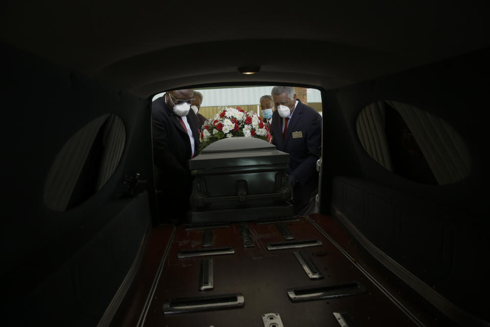 Mortician Cordarial O. Holloway, foreground left, funeral director Robert L. Albritten, foreground right, and funeral attendants Eddie Keith, background left, and Ronald Costello place a casket into a hearse on April 18, 2020, in Dawson, Ga. (AP Photo/Brynn Anderson)