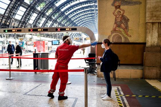 A passenger has her temperature taken to check for symptoms of Covid-19 before boarding a train to Milan’s Central Station, (AP)