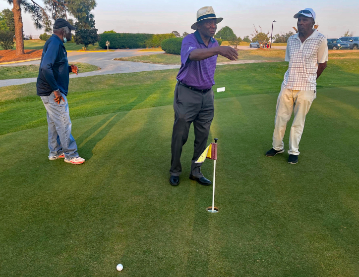 Caddies Tommy Bennett (in white), Buck Moore (dark blue), and Jariah Beard (purple) at Augusta Municipal Golf Course.