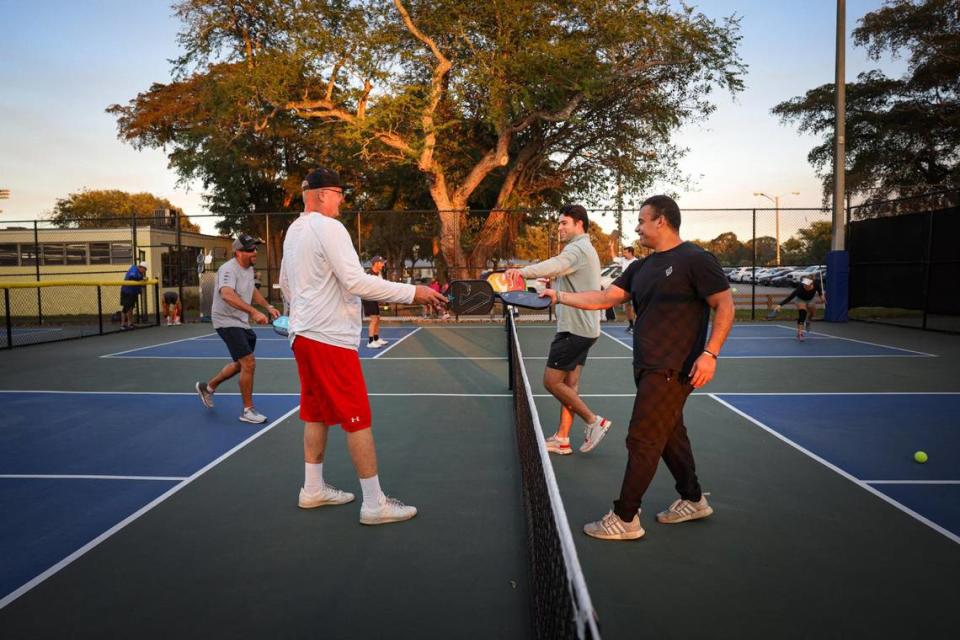 Scott VanPutten, left, AJ Consuegra, center, and Steven Marin end the pickleball game with a tap of paddles at Tropical Park courts on Monday, Feb. 13, 2023.