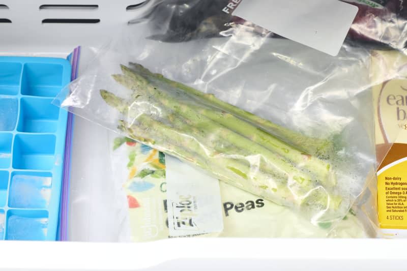 overhead shot of asparagus in a ziploc bag inside the freezer.