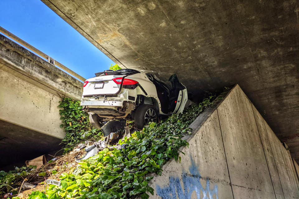 This photo provided by the California Highway Patrol shows the scene where a man fleeing from the CHP totaled his girlfriend's Maserati SUV after he careened up an embankment and slammed into the underside of an overpass, wedging the car under a freeway in Oakland, Calif., on Monday, April 12, 2021. (California Highway Patrol via AP)