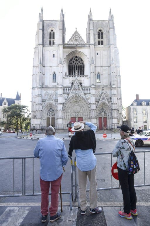 Des passants regardent la façade de la cathédrale Saint-Pierre-et-Saint-Paul de Nantes touchée par un incendie, le 19 juillet 2020 - Sebastien SALOM-GOMIS © 2019 AFP