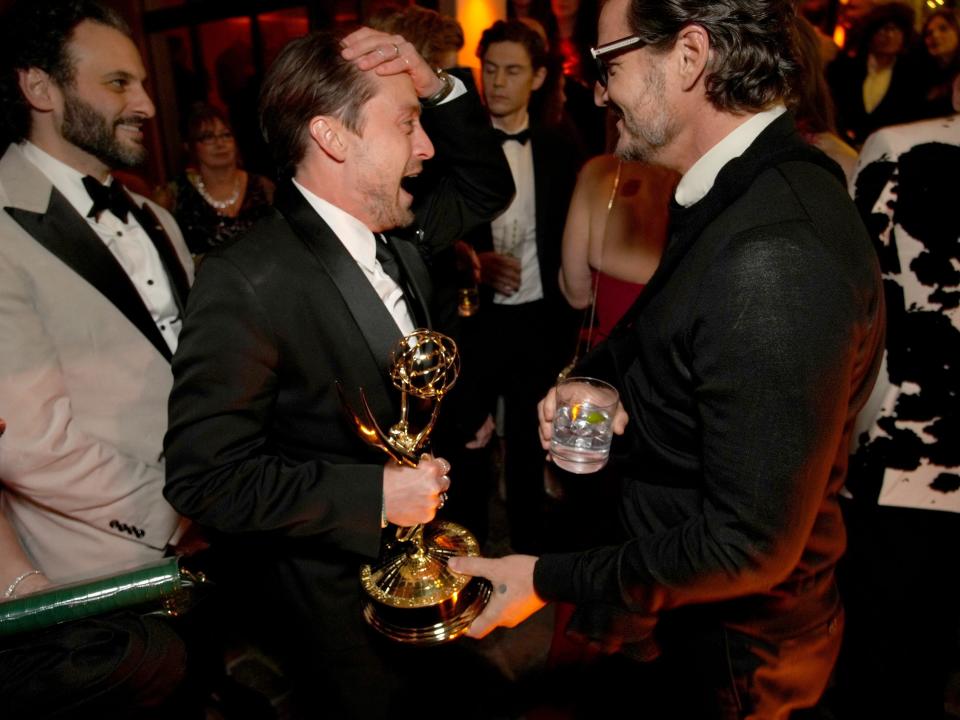 kieran culkin and pedro pascal speaking to each other. culkin has his hand on his head and is holding an emmy statuette, pascal is holding a drink one hand and has a hand on the statuette as well