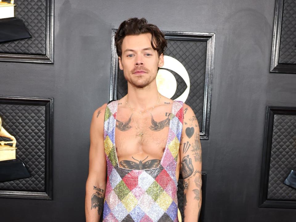 Harry Styles arrived on the red carpet in a multi-coloured sequin jumpsuit that revealed the bird tattoos on his chest (Getty Images)