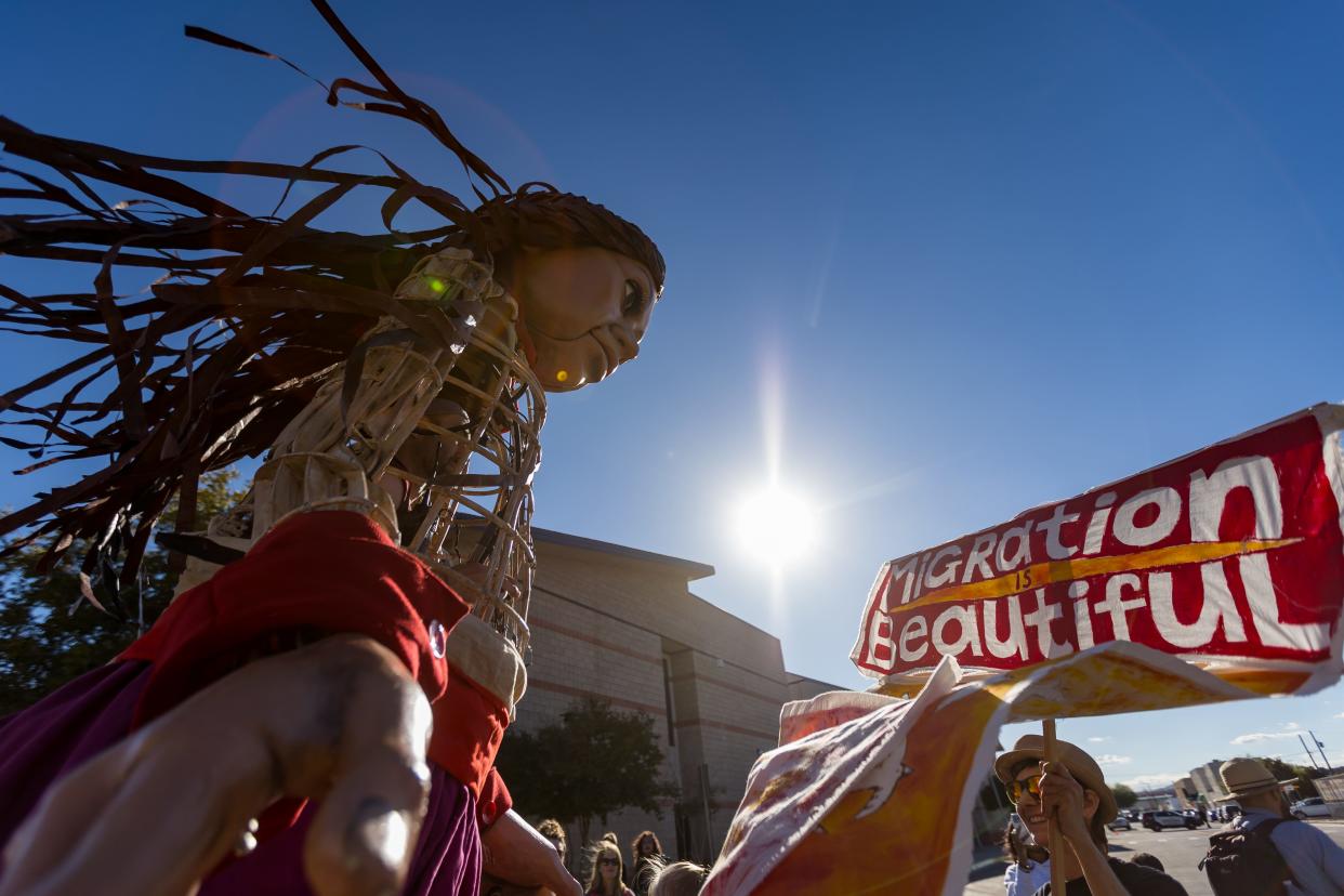 Little Amal, the 12-foot puppet of a ten-year-old Syrian child, is greeted with little bird puppets and a sign saying “Migration is Beautiful” at her first stop in El Paso at Armijo Park in Segundo Barrio on Wednesday, Oct. 25, 2023.