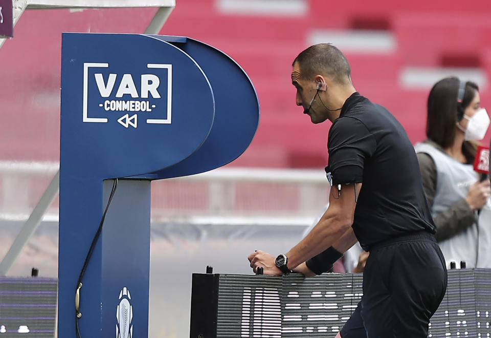 El árbitro uruguayo Esteban Ostojich revisa la repetición antes de descartar un penal a favor de Ecuador en un partido de la eliminatoria mundialista ante Perú, el martes 8 de junio de 2021 (AP Foto/Jose Jacome/Pool via AP)