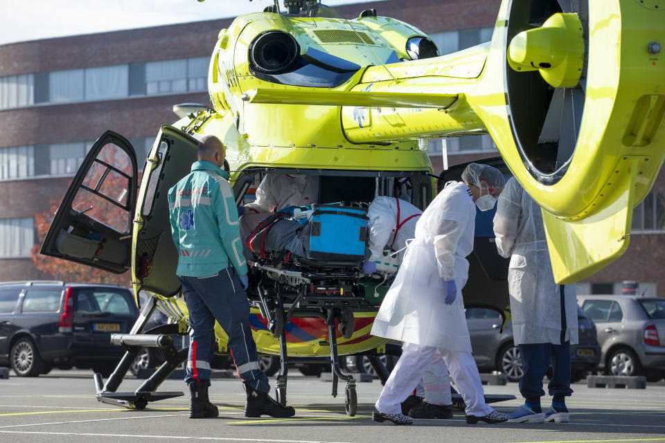 A COVID-19 patient is being carried into a helicopter at Flevoziekenhuis, or FlevoHospital, in Almere, Netherlands, Friday, Oct. 23, 2020. In the latest sign of the scale of the coronavirus pandemic sweeping across Europe, a helicopter is scheduled to start airlifting COVID-19 patients from the Netherlands to an intensive care unit in the German city of Muenster.(AP Photo/Peter Dejong)