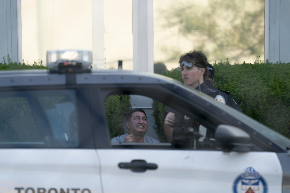 Toronto police officers comfort a man at the scene of a shooting in Toronto, Monday, June 17, 2024. (Arlyn McAdorey/The Canadian Press via AP)