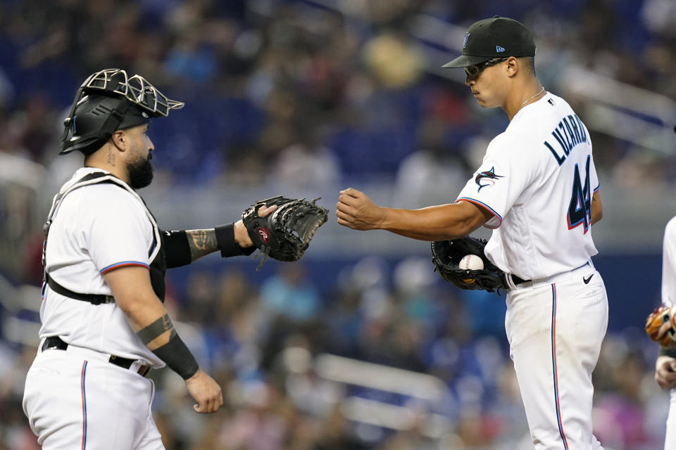 Miami Marlins starting pitcher Jesus Luzardo, right, bumps fists with catcher Sandy Leon as he is relieved during the seventh inning of a baseball game against the Cincinnati Reds, Sunday, Aug. 29, 2021, in Miami. The Marlins won 2-1. (AP Photo/Lynne Sladky)