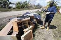 Andre McCourt throws away water logged furniture from his home Tuesday, Oct. 4, 2022, in North Port, Fla. Residents were cleaning up flooding damage after Hurricane Ian came ashore last week. (AP Photo/Chris O'Meara)